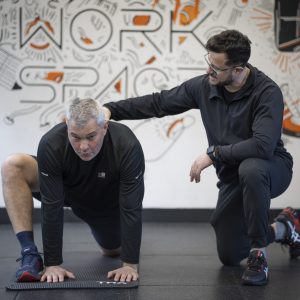 personal trainer helping man to do mobility drills in PT Workspace