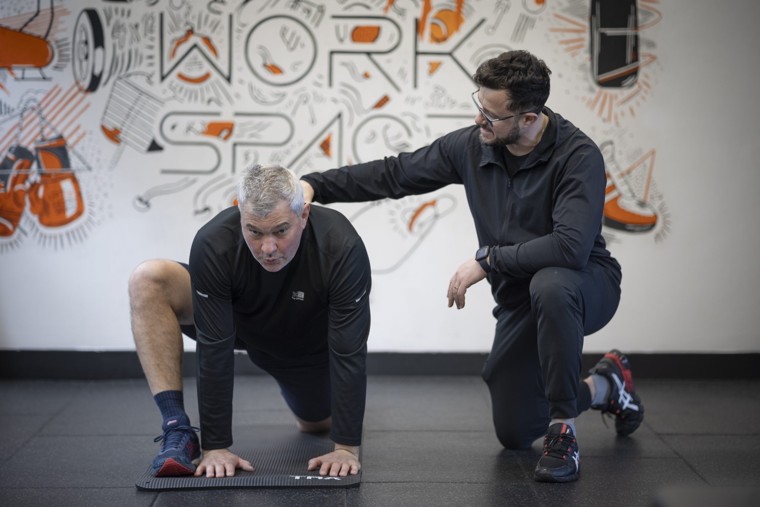 personal trainer helping man to do mobility drills in PT Workspace